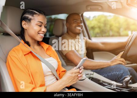 Young African American woman using smartphone while riding in a car Stock Photo