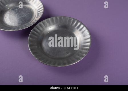 Studio shot featuring metal plates on a purple background. Focus on textures, metallic sheen, and minimalist design. Suitable for kitchenware, culinar Stock Photo