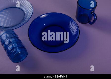 Minimalist setup featuring cobalt blue glass tableware. Includes dish, plate, drinking glass. Rich textures and balanced light. Conceptual still life Stock Photo