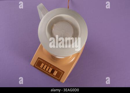 Still life photograph on purple backdrop. Vintage blender with peach base and white pitcher. Great contrast and copy space. Commercial use for healthy Stock Photo