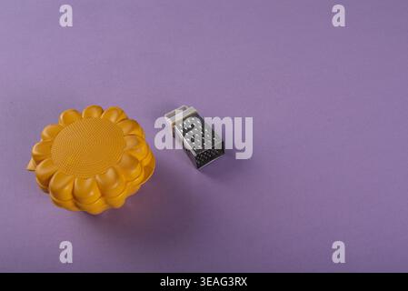 Still life of a yellow sunflower silicone mold and silver grater. Soft studio lighting accentuates textures. Shot for culinary, healthy eating, or cra Stock Photo