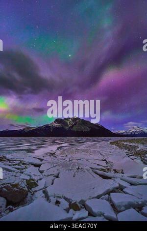 Frozen Lake Cracked Ice Snowcapped Mountain and Northern Lights in Winter Night Stock Photo