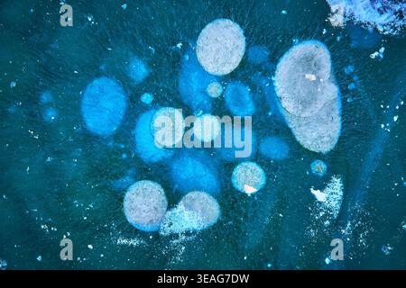 Aerial Frozen Lake Ice Patterns and Methane Bubbles in Vibrant Winter Blue Stock Photo
