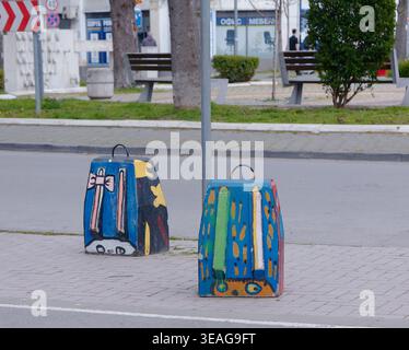 Varna, Bulgaria - April 20, 2026: Colorful concrete blocks in the shape of colored school backpacks are placed on a city street to prevent parking, wi Stock Photo