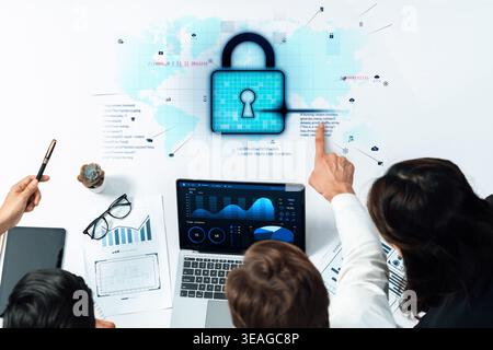 Professionals collaborate to enhance cybersecurity measures, analyzing data with graphs and charts on a laptop, discussing effective strategies agains Stock Photo