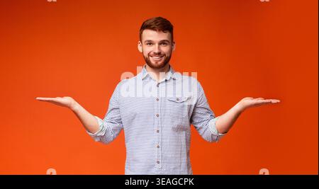 Young Man Smiling and Posing With Outstretched Arms in Front of an Orange Background Stock Photo