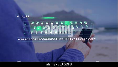 Holding smartphone, mature man in blue knit sweater typing at beach, hologram keyboard overlay Stock Photo