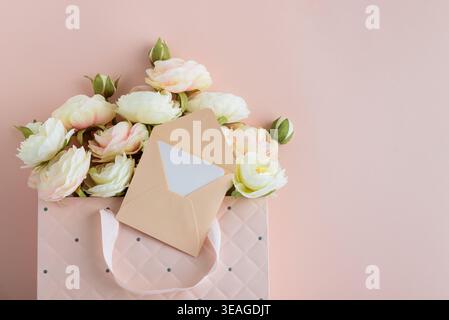 Festive composition featuring a quilted pink gift bag filled with cream and blush artificial rose flowers, accented by a white ribbon bow and gift car Stock Photo