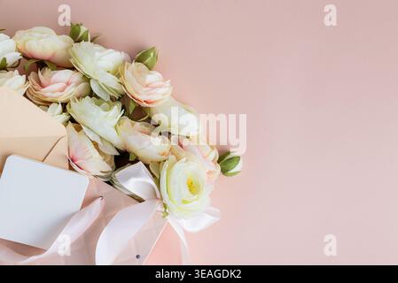 Festive composition featuring a quilted pink gift bag filled with cream and blush artificial rose flowers, accented by a white ribbon bow and gift car Stock Photo