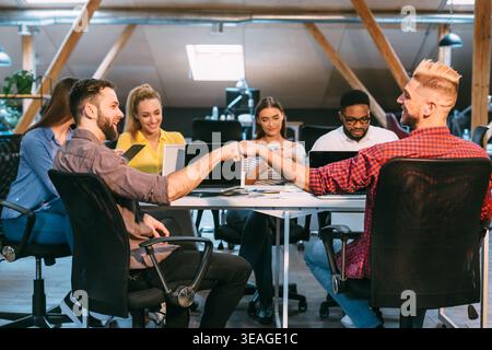 Team Members Engaging in a Handshake During a Collaborative Meeting in a Modern Office Space Stock Photo
