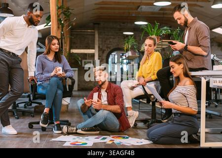 Team Collaboration in Modern Office Discussing Project Details on Printed Graphs and Charts Stock Photo