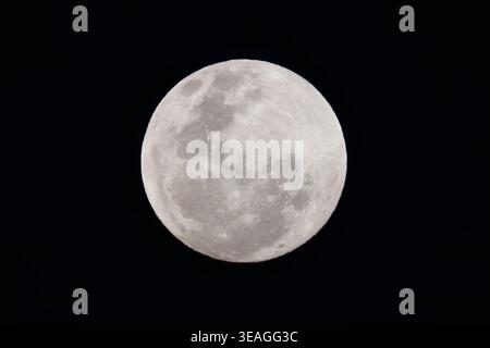 Detailed full moon isolated against a deep black night sky, showing visible craters and surface features. Stock Photo