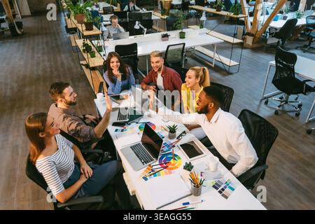 Creative coworkers high fiving at desk in office Stock Photo