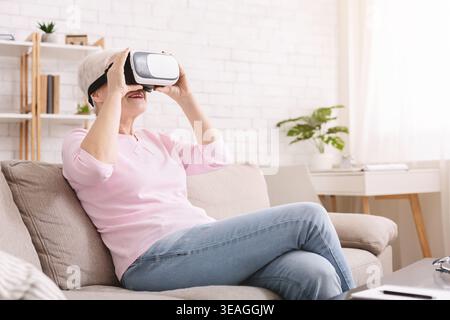 Senior Woman Using Virtual Reality Headset on a Couch in Living Room Stock Photo