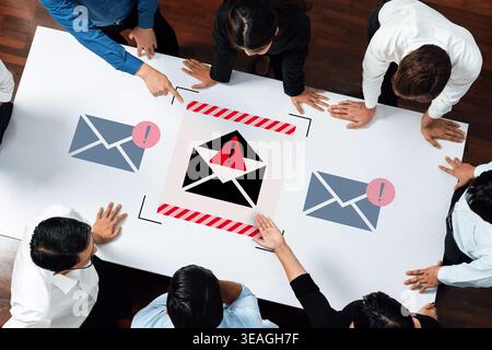 A diverse group of business professionals engages in a serious discussion about the dangers of email phishing attacks, emphasizing cybersecurity aware Stock Photo