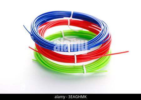 Coils of blue, red, and green plastic filament on white background Stock Photo