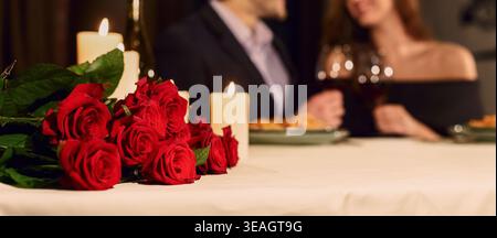 Couple Sharing a Romantic Dinner With Roses and Candles in a Cozy Setting Stock Photo