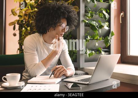 Confident young man working on laptop sitting in cafe Stock Photo