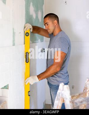 Portrait of young man dressing casual clothes using manual level in process of renovation Stock Photo