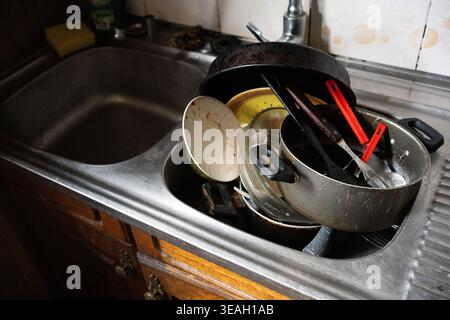 Mountain of Dirty Dishes and Pots Piled High in a Kitchen Sink, Waiting to be Washed Stock Photo
