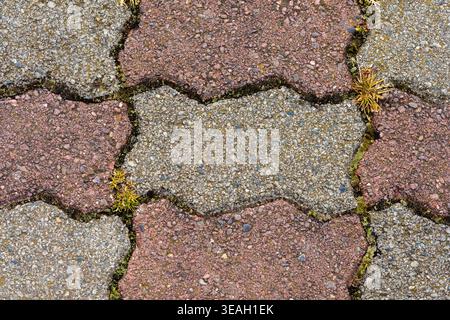 Interlocking Concrete Paver Stones Texture: Zigzag Pattern in Gray and Reddish-Brown Colors, Abstract Background of Rough, Granular Pavement Bricks fo Stock Photo