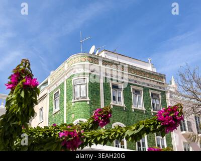 Historic building with green azulejo tiles framed by pink bougainvillea flowers clear blue sky in Luis de Camoes Square lagos Portugal green house Stock Photo