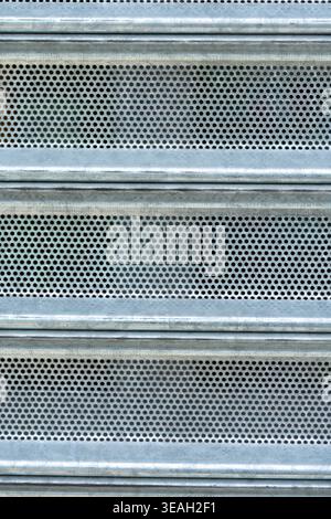 Close-up of Industrial Roller Door with Grid of Small Holes and Metallic Surface Stock Photo
