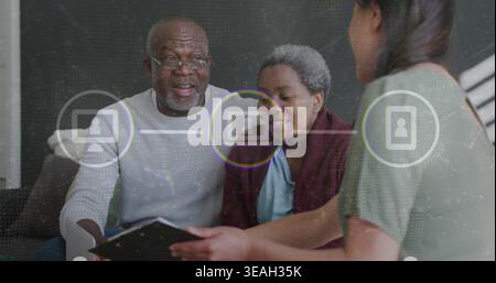 Reading couple on sofa at home, man wearing glasses, advisor holding clipboard with digital icons Stock Photo