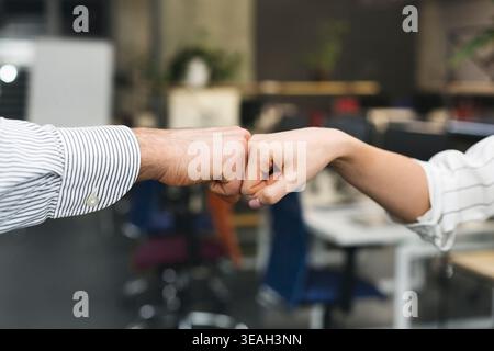 Fist Bump Between Colleagues in Modern Office Setting During Workday Stock Photo