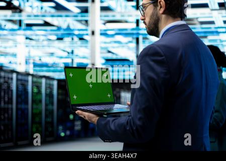 Isolated screen laptop used by data center system administrator to conduct security audits and against cyber threats. Worker uses chroma key notebook to implement cybersecurity measures in server hub Stock Photo