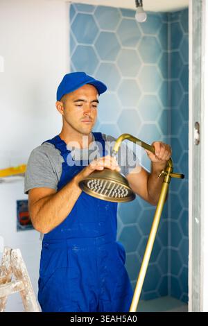 Plumbing specialist assembling tubes of shower in bathroom Stock Photo