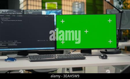 Green screen PC in empty startup office with programming language script running on monitors. Mockup computers in AI industry startup workspace leveraging coding software enhancing system automation Stock Photo