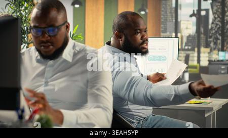 Professional business people analyze documents and graphs for risk assessment. Diverse work team collaborates on report writing, forecasting and performance metrics in office. Stock Photo
