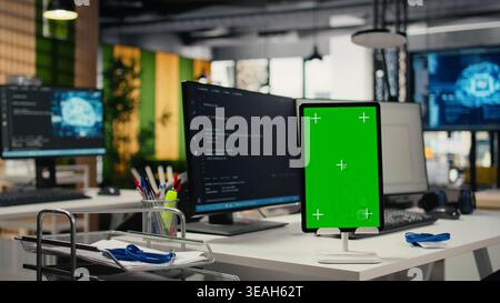 Green screen tablet in empty startup office with neural network program running on monitors. Mockup device in AI tech agency leveraging machine learning tech enhancing servers automation Stock Photo