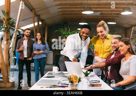 Young colleagues working on laptop and discussing new project Stock Photo