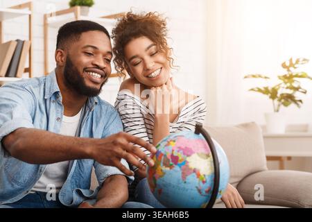 Young Couple Exploring the World Together Using a Globe in a Cozy Living Room Stock Photo