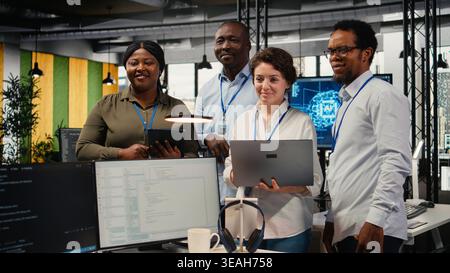 Portrait of smiling engineering team in office automating workflows using artificial intelligence tech. Happy coworkers refining deep learning computational models for faster processing, camera A Stock Photo