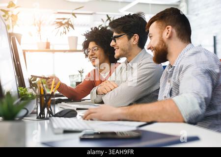 Three People Collaborate in a Bright Workspace on a Project Involving Digital Technology Stock Photo
