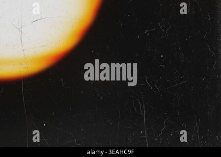 Bright yellow circular lens flare on dark retro film background with dust Stock Photo