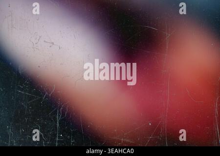 Diagonal blurred light leak overlay with pink and red hues on scratched dark film Stock Photo