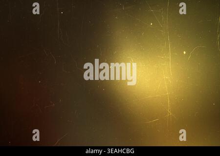 Golden warm light leak on a scratched dark vintage film texture background Stock Photo