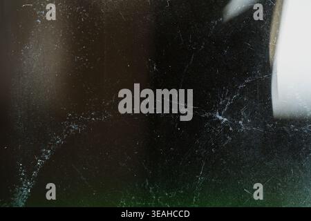 Dark textured background with heavy scratches and bright light flare on the edge Stock Photo