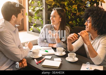 Young colleagues discussing project and marketing strategy in cafe Stock Photo