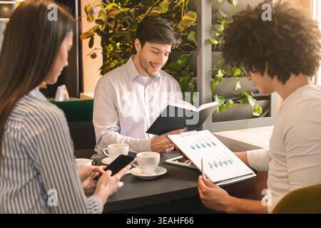 Young millennial colleagues having business lunch in cafe Stock Photo