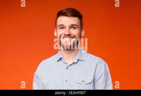Smiling Man With Light Beard Poses in Front of an Orange Background During Daytime Stock Photo
