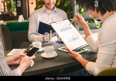 Colleagues Discussing Project Progress Over Coffee in a Modern Workspace in the Afternoon Stock Photo
