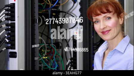 Standing woman in blue shirt checking switches at data center, numeric overlays, cables, copy space Stock Photo