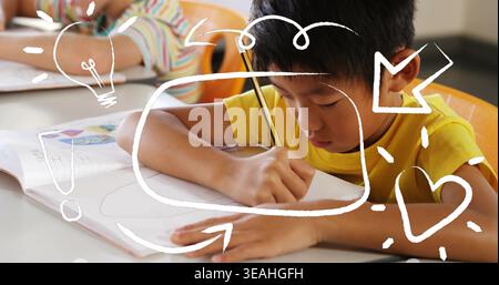 Writing boy in yellow T-shirt focusing on workbook at school, holding pencil and graphic overlays Stock Photo
