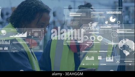 Two workers in hi-vis vests reviewing tablet at warehouse, with AR HUD, red hearing protection Stock Photo