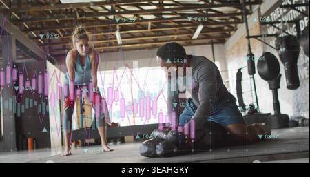 Leaning female athlete wearing gear in gym kneeling coach fixing wraps by punching bags with charts Stock Photo